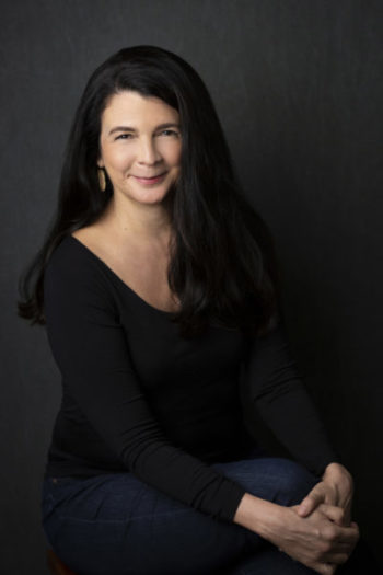 Writer Heather Sellers is smiling and wearing black. Her long hair is over her shoulder.